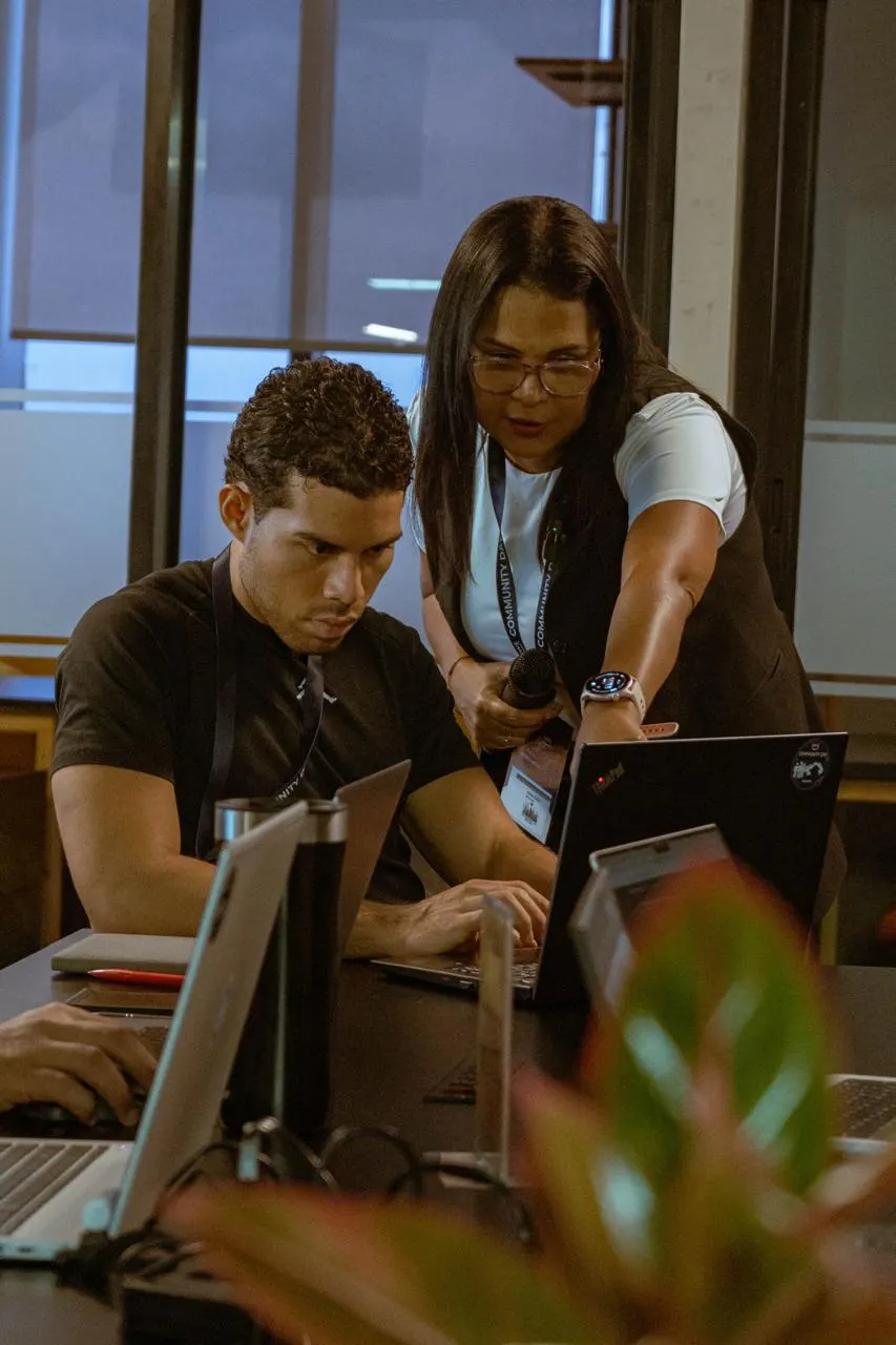 Keisa Ávila con micrófono ayudando a un participante en un workshop de AWS Community Day Panamá